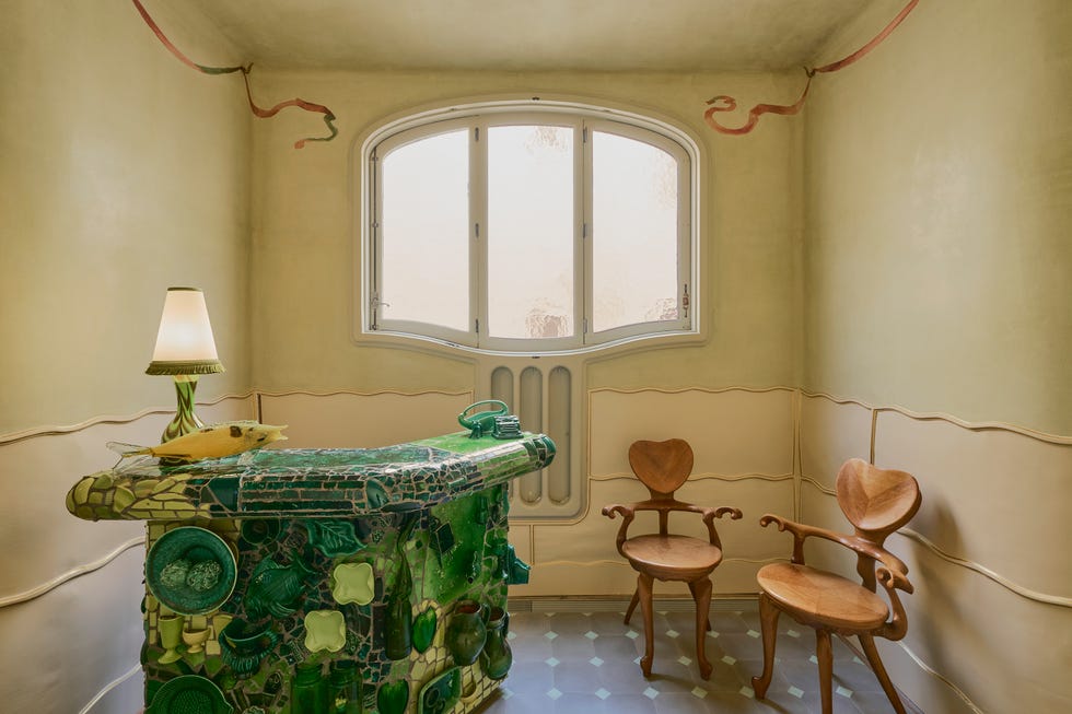 Interior space featuring a decorative green counter, two wooden chairs, and a window with soft lighting.