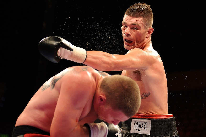 A boxer ducks as his opponent throws a punch over his head during a match.