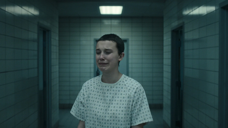 Millie Bobby Brown's Eleven stands in a hallway crying in Stranger Things