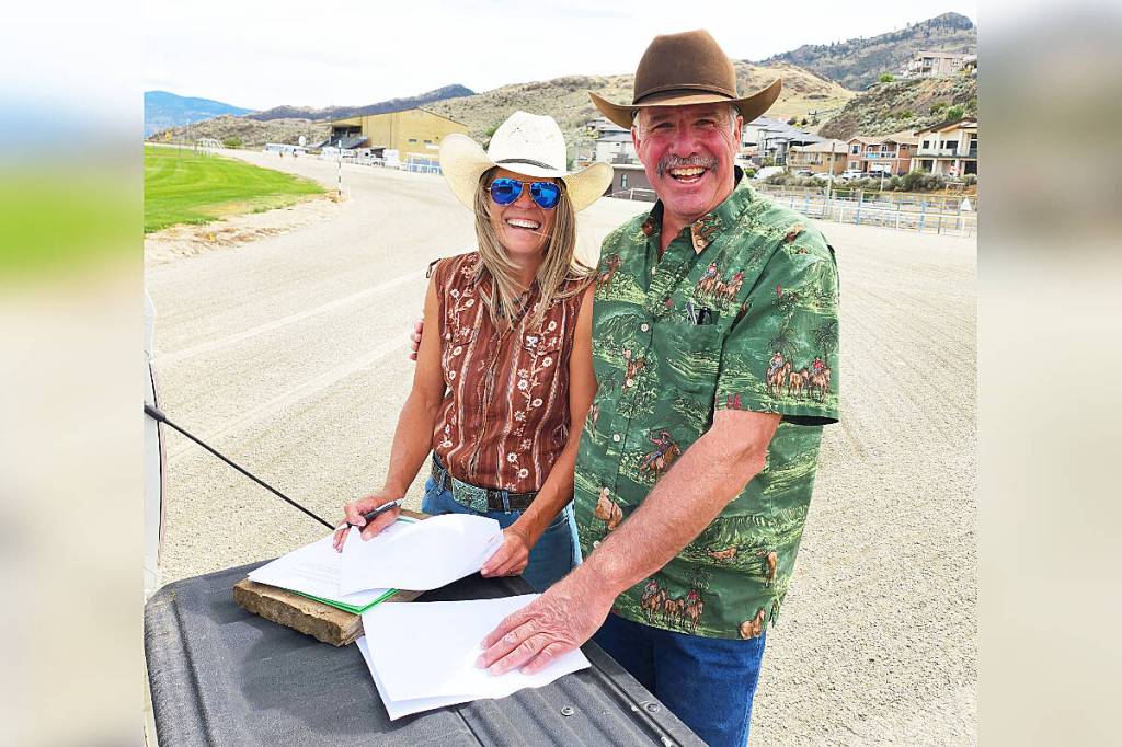 Rebekka Lim, president of the Desert Park Exhibition Society, and Kelly MacMillan, president of the Western Canada Horse Racing Association, sign papers on the tailgate of MacMillan’s truck July 3 at Desert Park Raceway in Osoyoos. Their signatures formalized an agreement between the two groups to bring harness racing to Osoyoos beginning in September, 2026. (Photo submitted to Cloverdale Reporter/WCHRA)