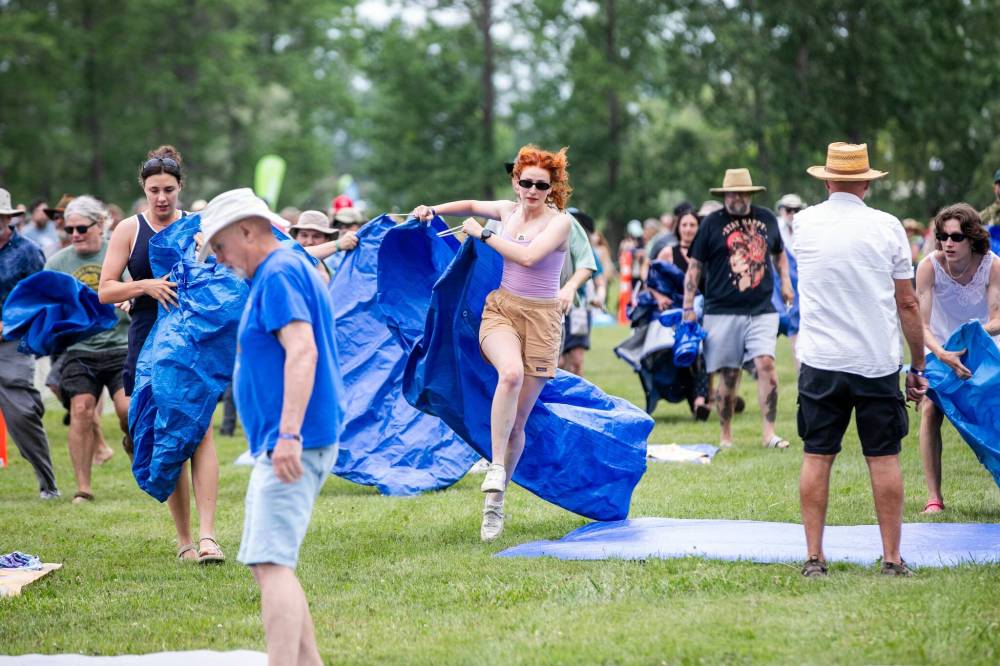 MIKAELA MACKENZIE / FREE PRESS
Annie Hollander hustles to set up a tarp near the front of the stage as the Winnipeg Folk Festival kicks off.