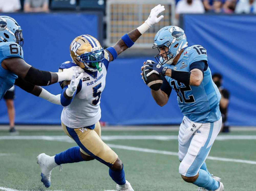JOHN WOODS / THE CANADIAN PRESS
Toronto Argonauts quarterback Chad Kelly escapes the tackle by Winnipeg Blue Bombers’ Willie Jefferson. Jefferson had two quarterback takedowns during Friday’s game.
