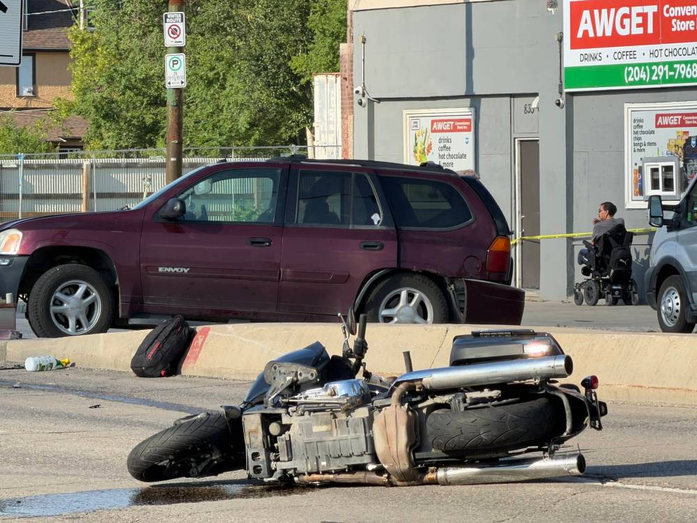 MORGAN MODJESKI / FREE PRESS
A motorcycle carrying two passengers involved in a crash lays on its side in the middle of Main Street on Friday.