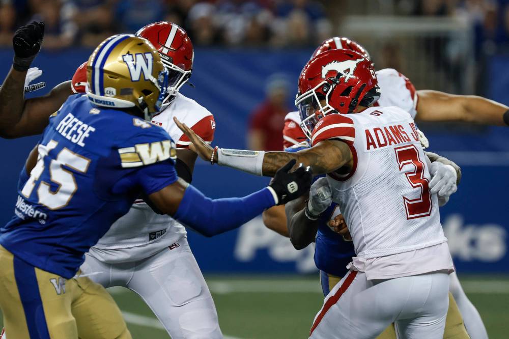 JOHN WOODS / THE CANADIAN PRESS
Calgary quarterback Vernon Adams Jr. gets sacked by Winnipeg Blue Bombers David Reese (45) and Nuer Gatkuoth (40) during second-half CFL football action in Winnipeg.