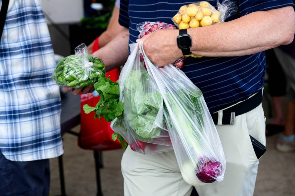 Mike Sudoma / Free Press
A shopper with two hands full of produce waits in line to pay Saturday morning.