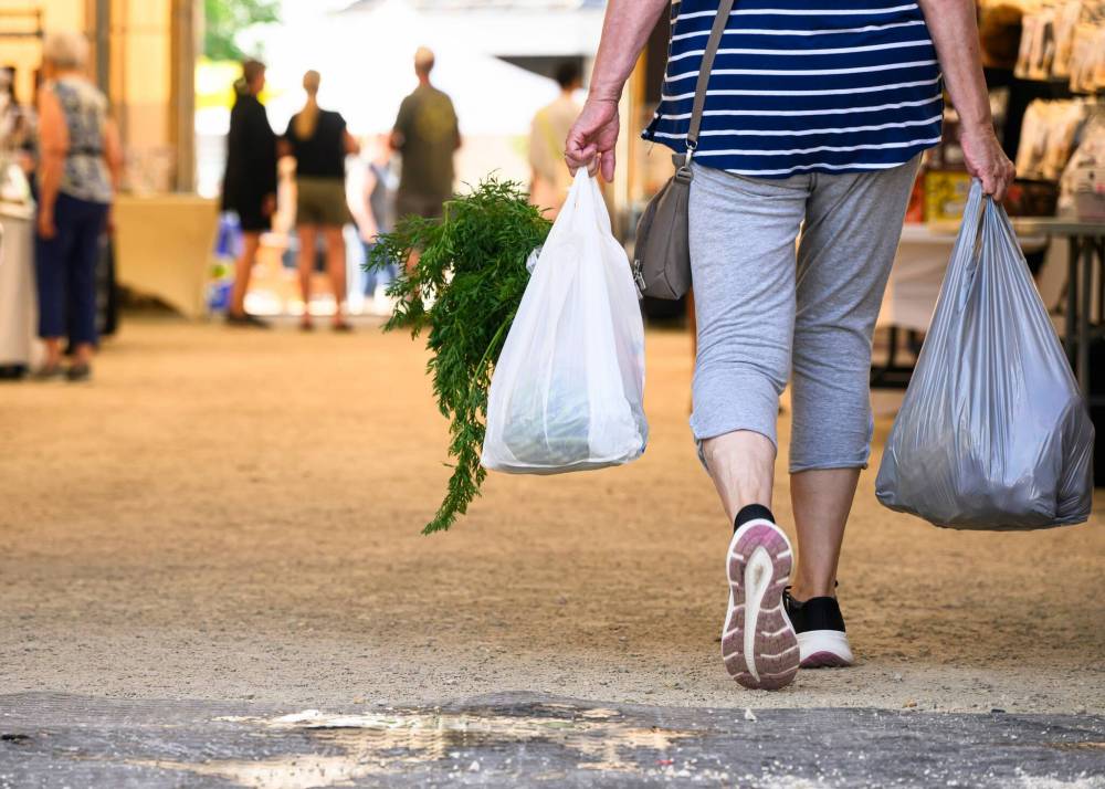 Mike Sudoma / Free Press
A shopper with two full grocery bags walks through St. Norbert Farmers Market Saturday morning.