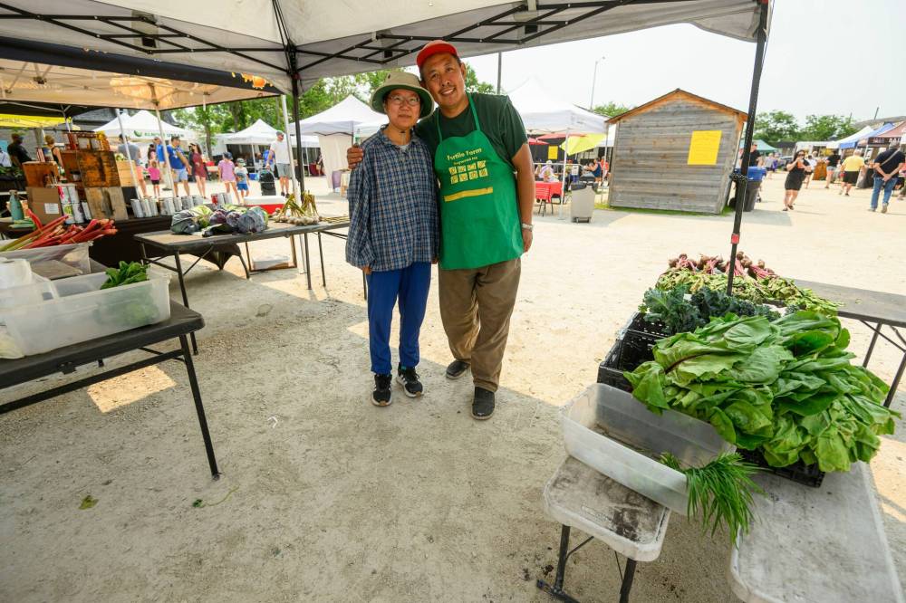 Mike Sudoma / Free Press
Ming Zhai and Tom Wang of Fertile Farms hang out under their booth’s canopy after almost fully selling out of their inventory by 1:30 p.m.