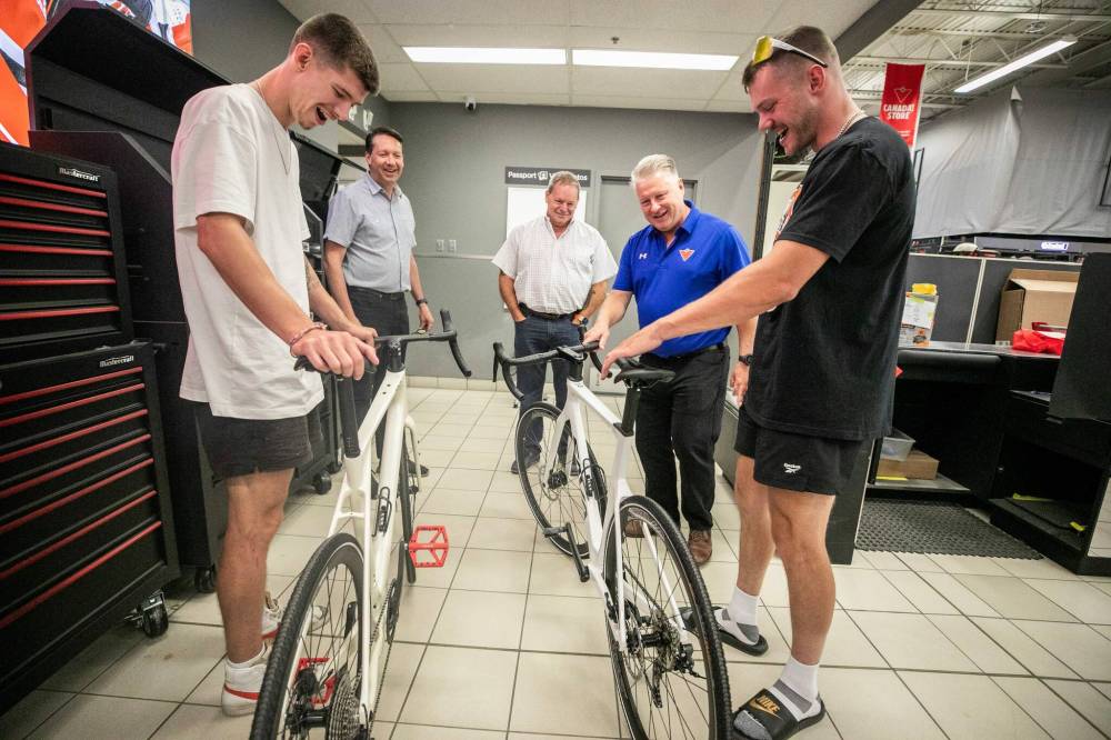 MIKAELA MACKENZIE / FREE PRESS
Thomas Clark (left) and Val Duquenne greet Canadian Tire folks Brad Elliott (left), Marc Gaudreau, and Chris Coenen with their new bikes on Monday.