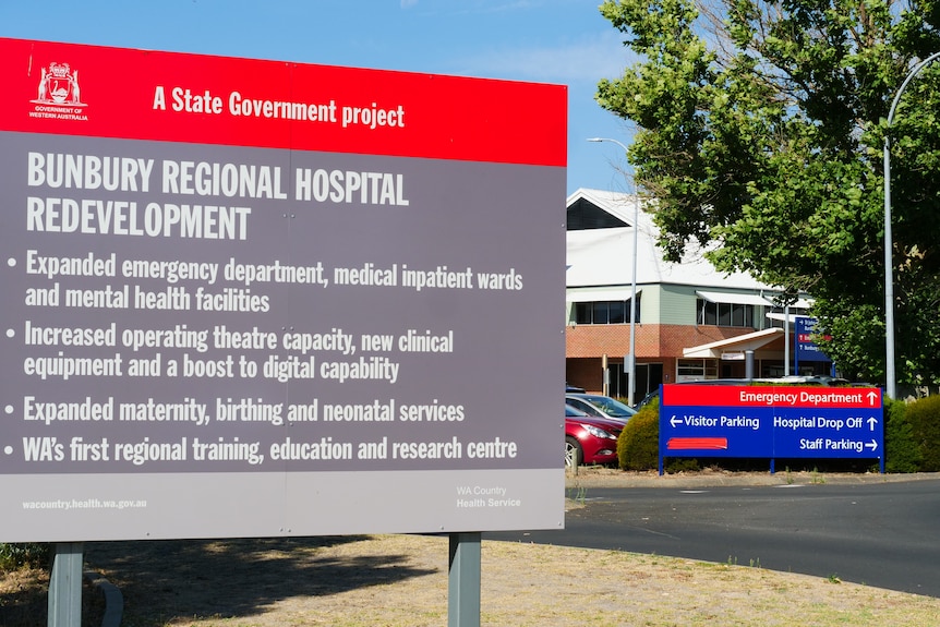 A red and grey sign outside a hospital outlining the redevelopment plans.