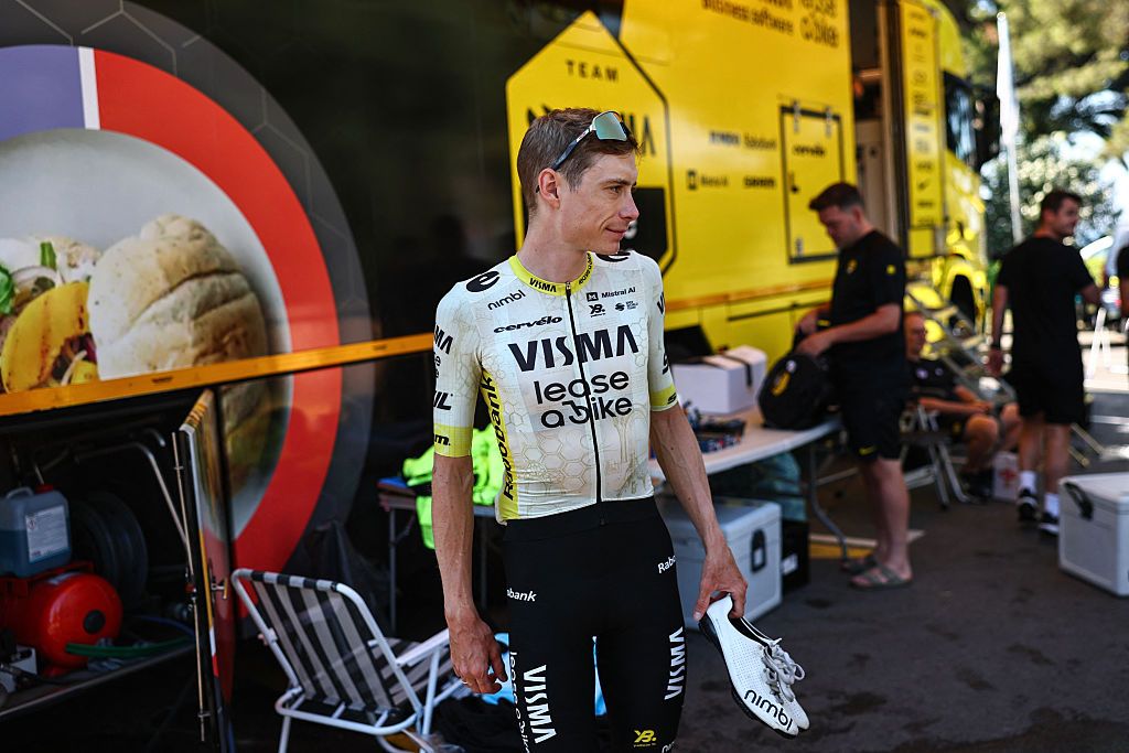 Jonas Vingegaard wearing the light rest day jersey standing by the team bus