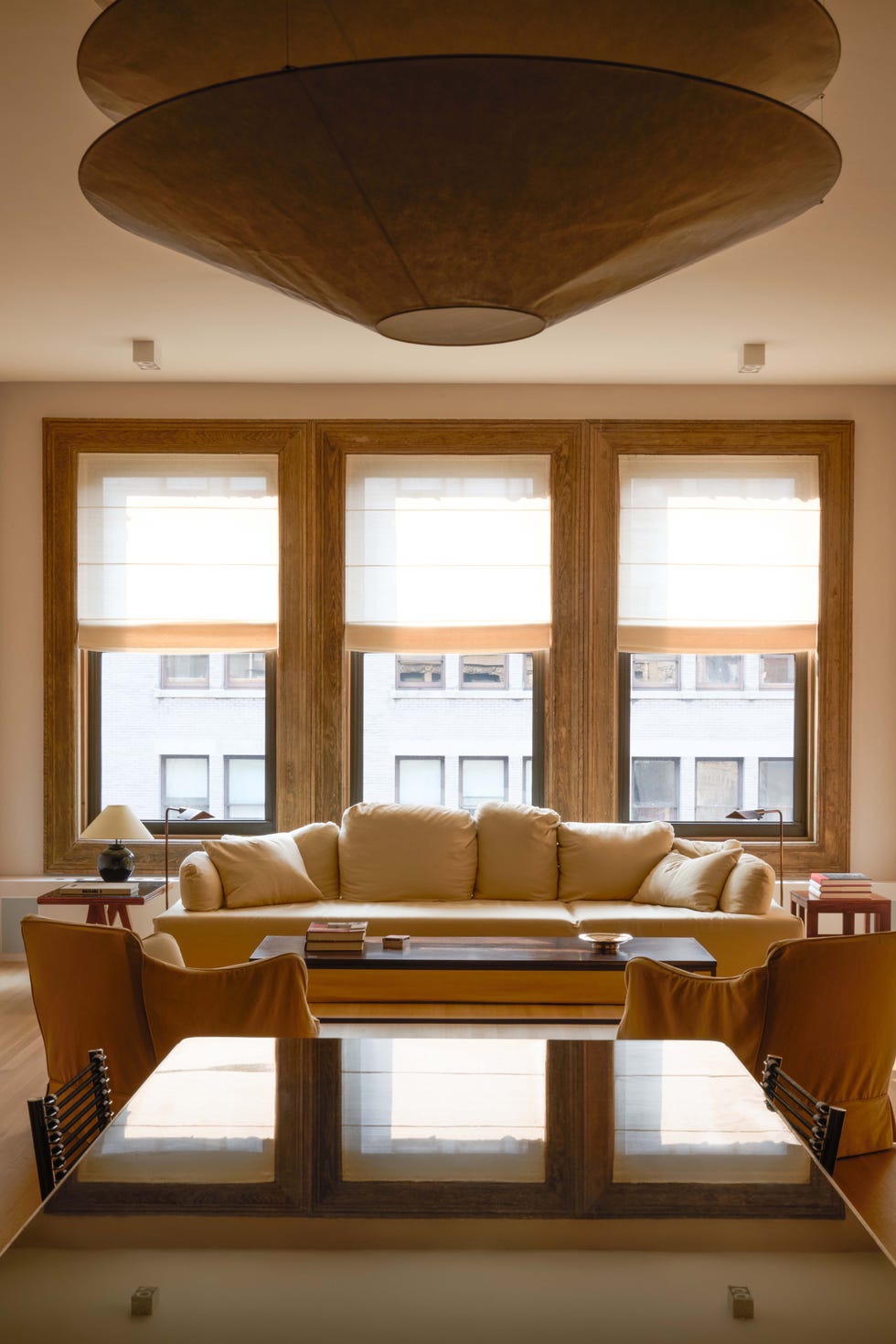 Modern living room featuring a light-colored sofa, a wooden table, and large windows with natural light.