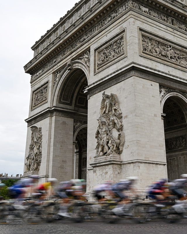 Cyclists racing past the Arc de Triomphe under a cloudy sky. Cyclists racing past the Arc de Triomphe under a cloudy sky.