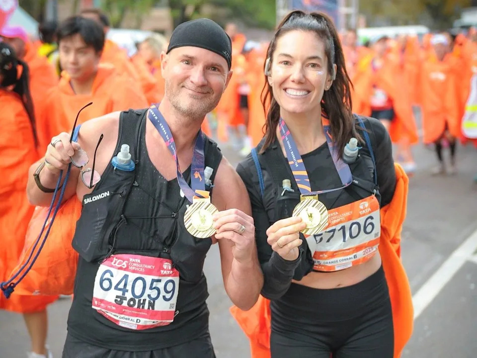 Connie DeSousa and John Jackson holding their medals just after completing the New York City marathon in 2025.