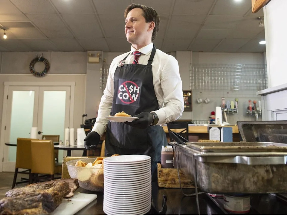 Transportation Minister Devin Dreeshen poses in an anti-cash cow apron while announcing restrictions to photo radar in December 2024.