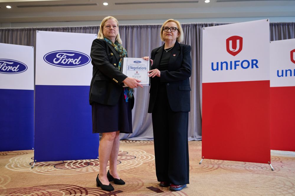 Ford Canada Vice President Human Resources Meredith Keenan, left, and Unifor National President Lana Payne exchange a negotiation binder to mark the opening of bargaining between Unifor and Ford Motor Company, in Toronto, on Monday, June 22, 2026. THE CANADIAN PRESS/Sammy Kogan