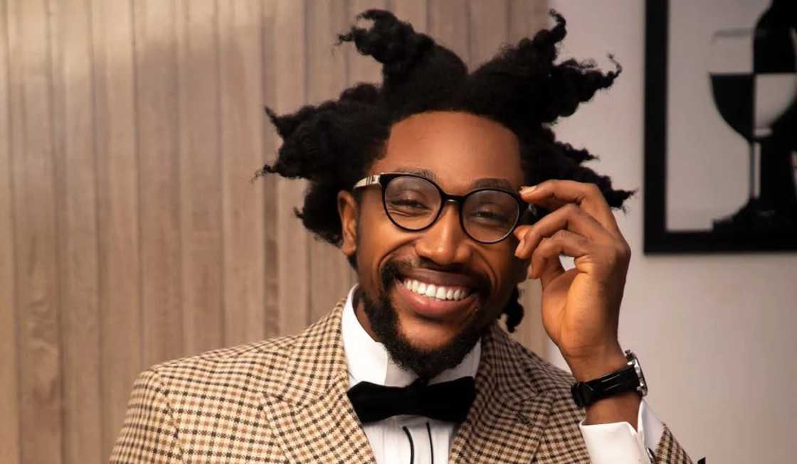 Cassi from BBNaija holds his glasses in a pose