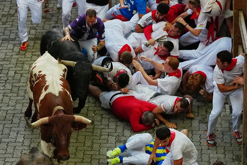 Revelers fall next to Jandilla's fighting bull during the eigth running of the bulls at the San Fermín festival in Pamplona, Spain, Tuesday, July 14, 2026. (AP Photo/Miguel Oses)