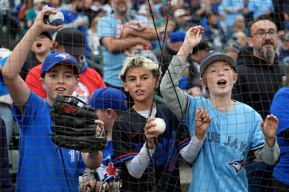Toronto Blue Jays fans with balls and markers hope to get an autograph prior to first inning MLB American League Championship Series game 4 baseball action between the Seattle Mariners and the Toronto Blue Jays, in Seattle, Thursday, Oct. 16, 2025. THE CANADIAN PRESS/Frank Gunn