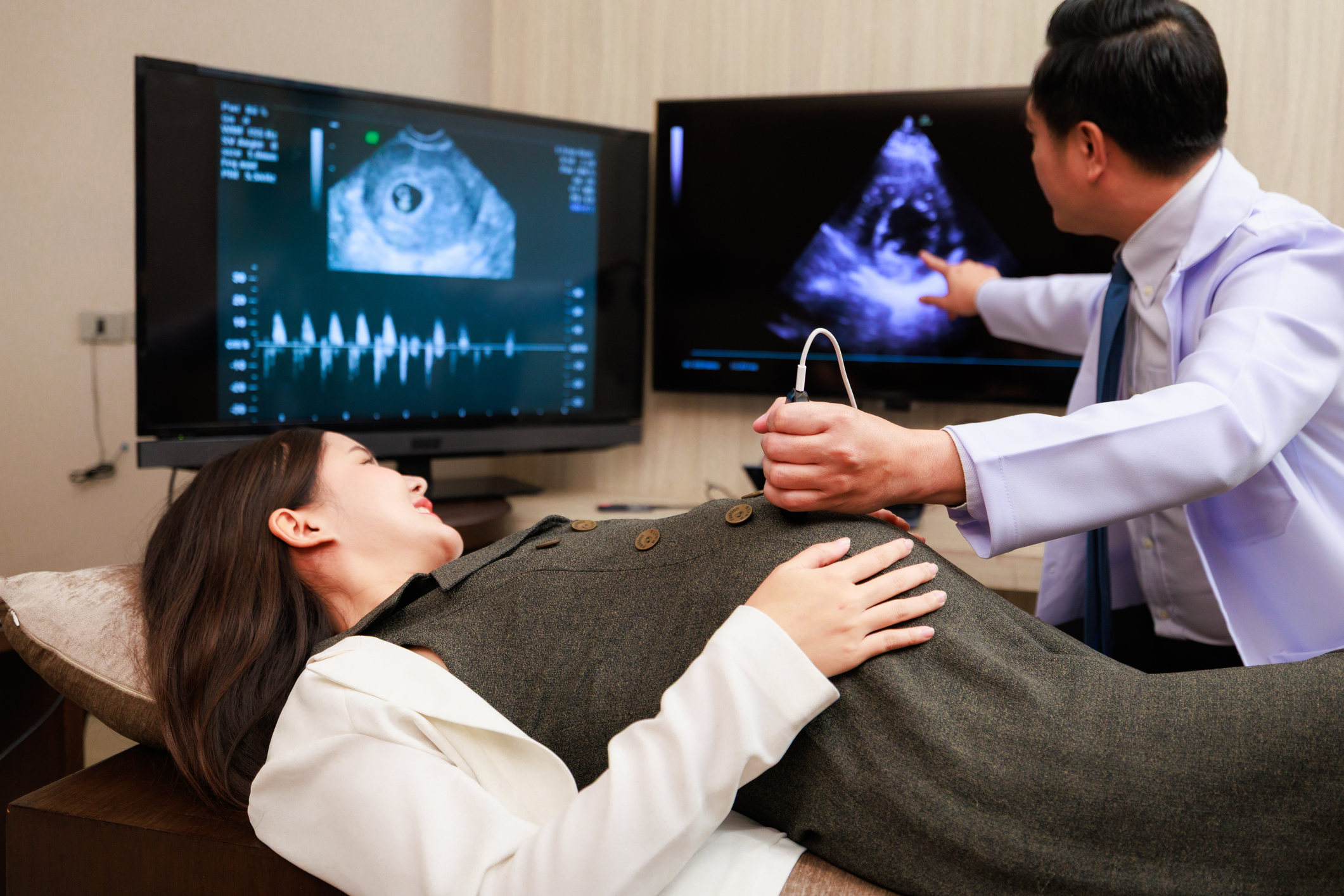A woman lays on a table with a man giving her an ultrasound