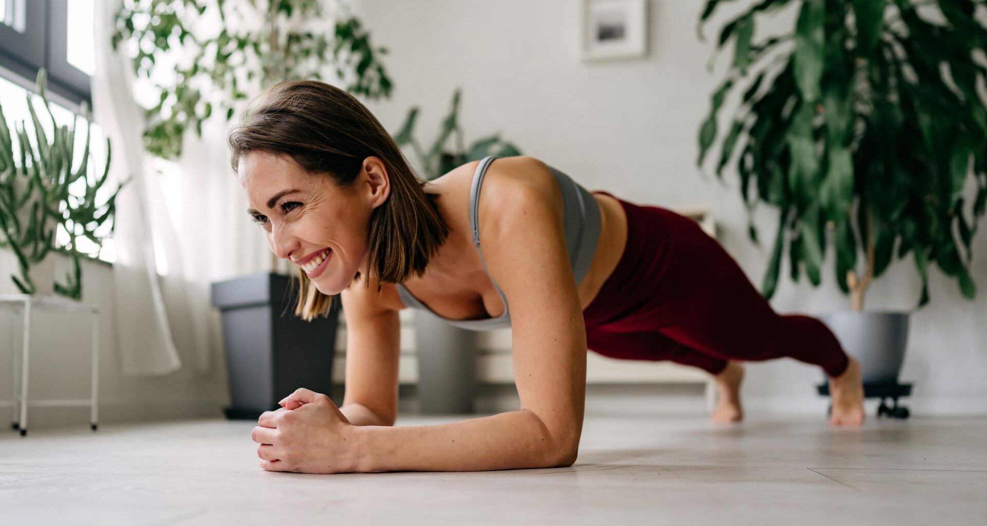 Woman setting up for plank rows exercise at home, smiling on floor