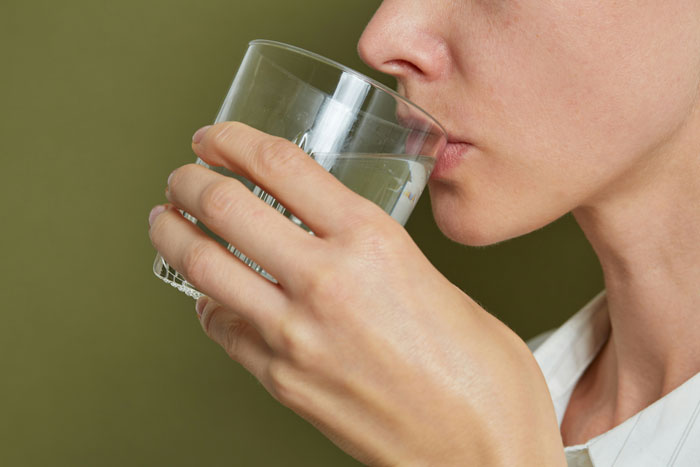 A patient drinking water, potentially failing to outsmart their doctors regarding hydration advice.