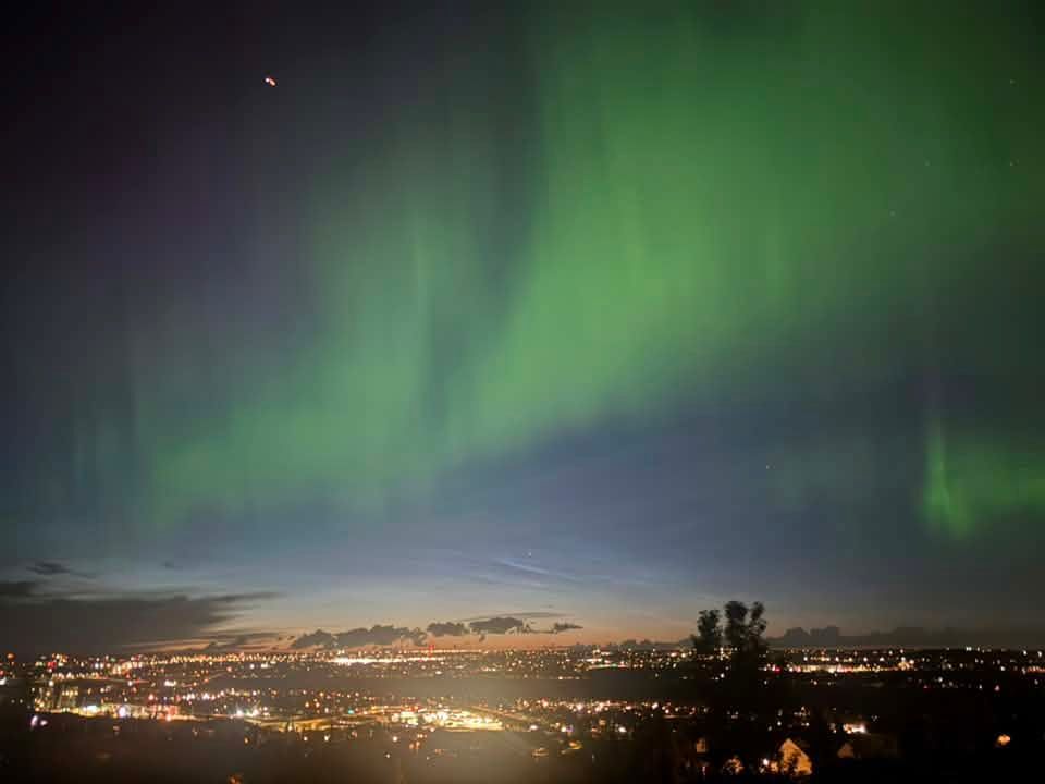 Green waves of the aurora borealis shine above Calgary's skyline as seen from Banff Coach Road S.W. shortly before midnight on July 3. Photo Courtney Fry**