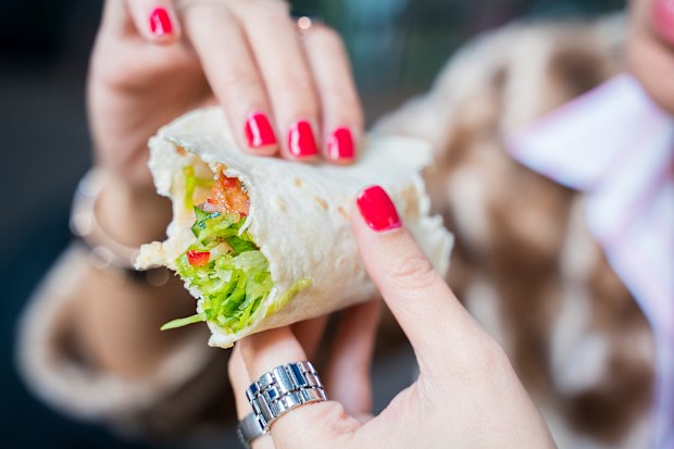 Stock image of a woman eating a wrap