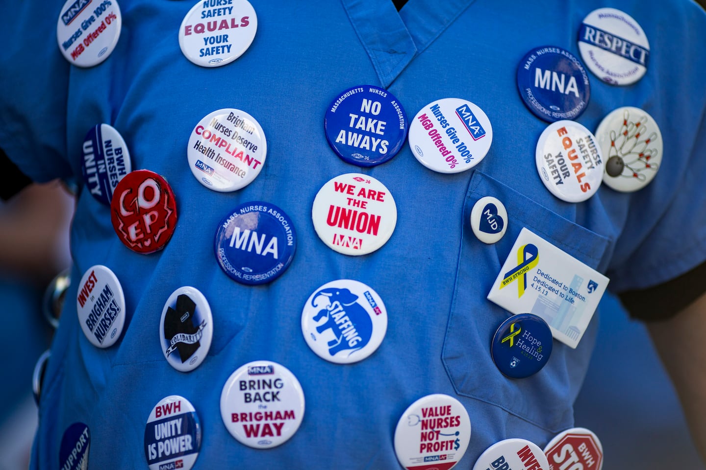 Protest buttons were pinned to the scrubs of a nurse during the first day of the nurses strike outside Brigham and Women's Hospital on Wednesday.