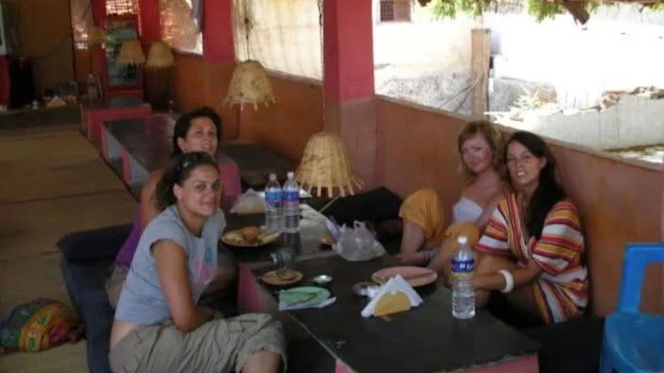 Lowri eating with friends in India in 2007. Four girls sit around a table wearing summer clothing.