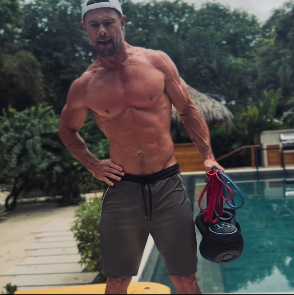 shirtless man holding kettlebell and resistance bands by a pool. shirtless man holding kettlebell and resistance bands by a pool.