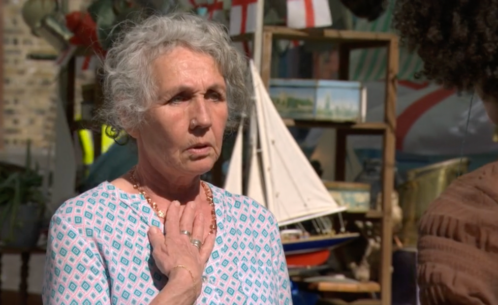elderly woman with hand on chest, model ship in background elderly woman with hand on chest, model ship in background