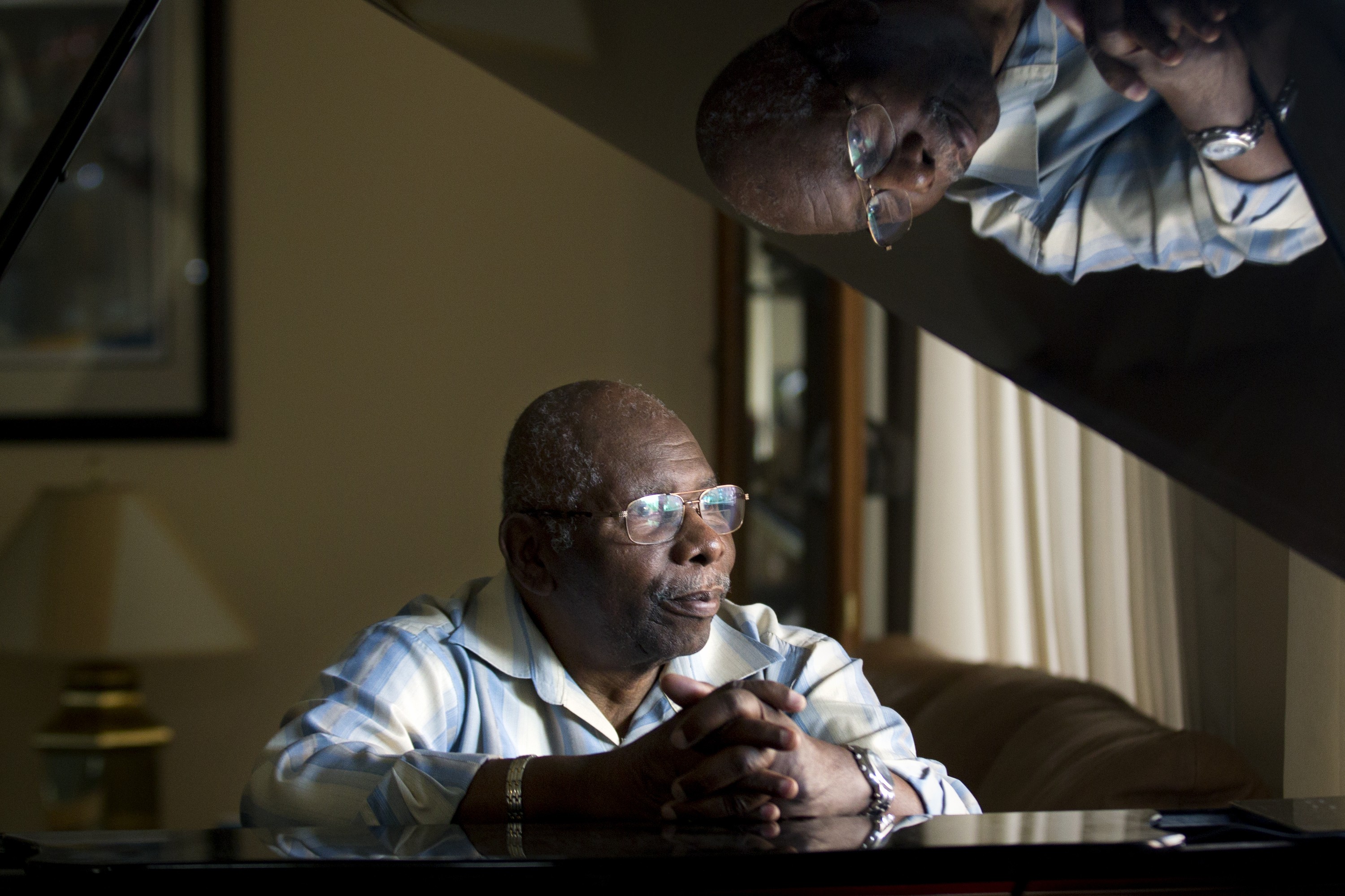 Oliver Jones sits at a grand piano in his home.