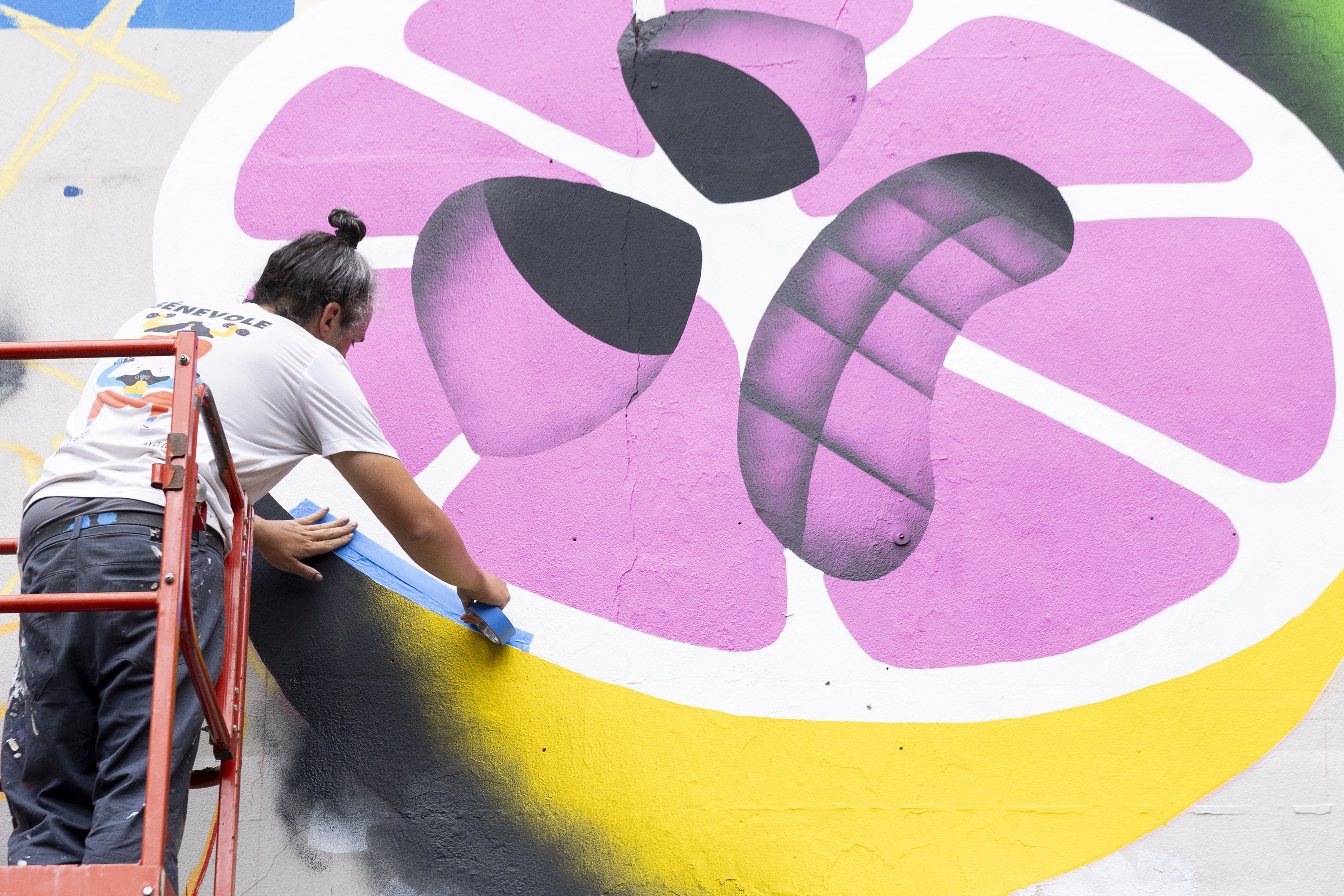 An artist paints a mural on a wall. 