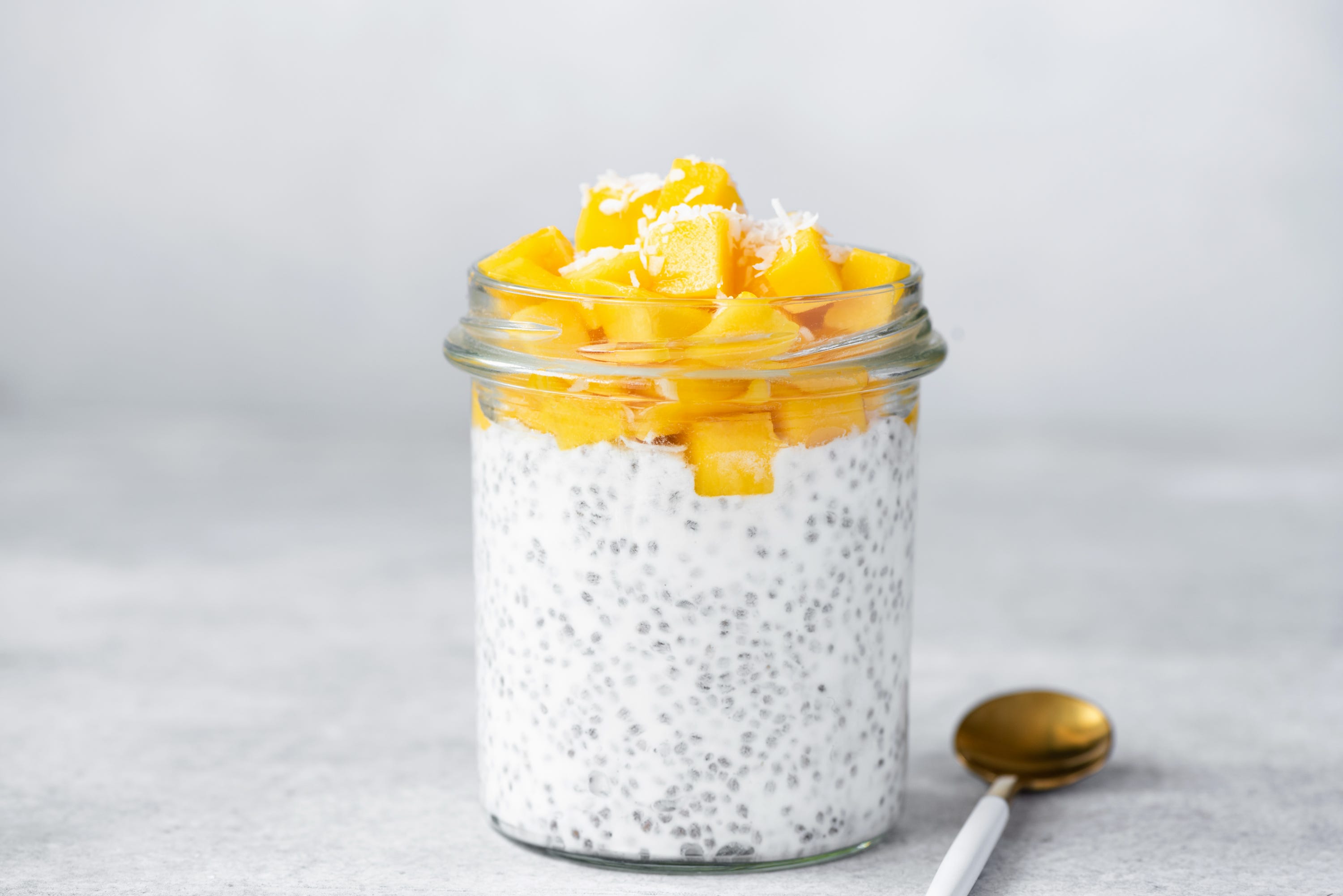 Close up of chia seed pudding topped with mango pieces in jar