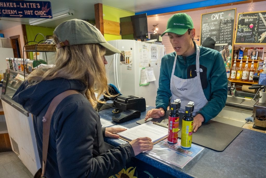A woman orders bear spray at a cafe counter.
