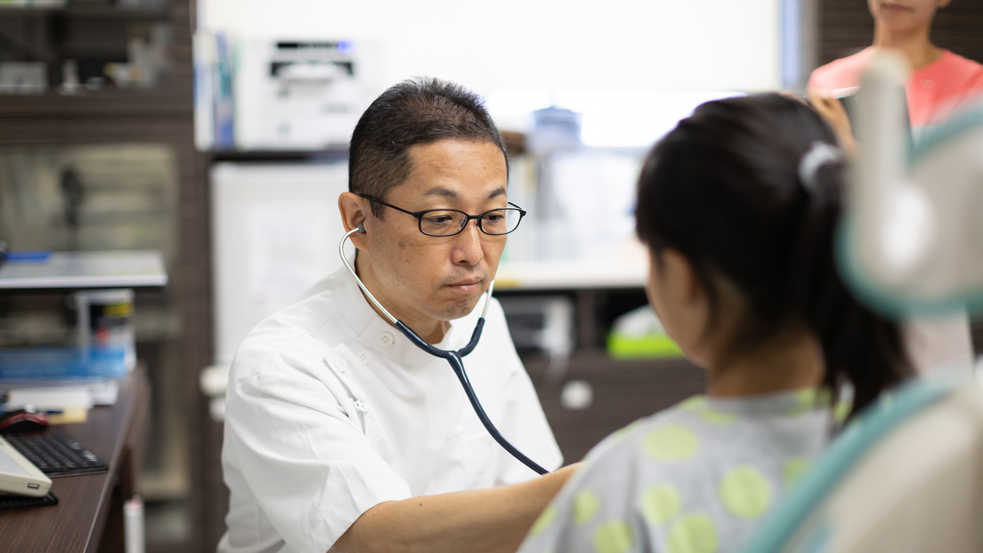 A doctor examines a girl with a stethoscope.