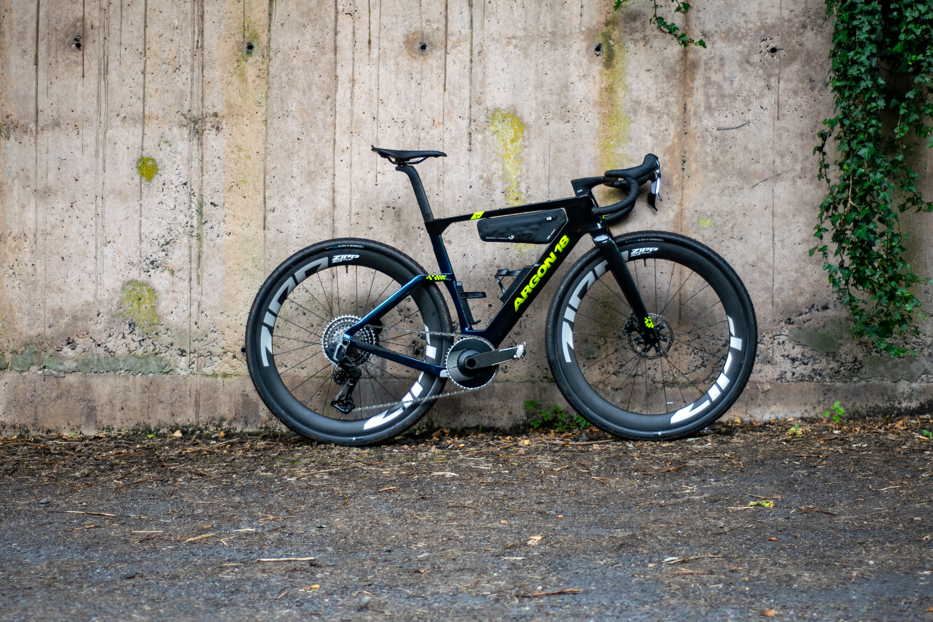 An Argon 18 Anti Matter gravel bike leaning against a concrete wall.