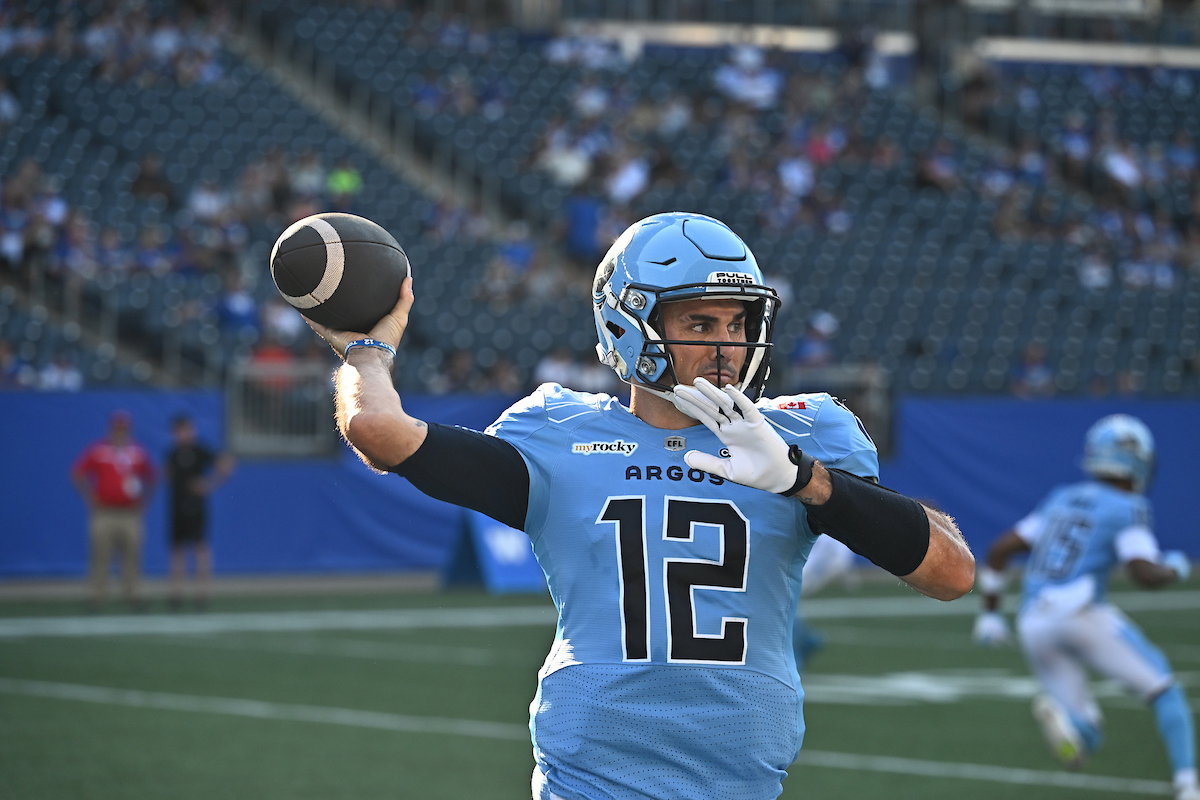 A football player in a light blue uniform with the number 12 prepares to throw the ball during a game.