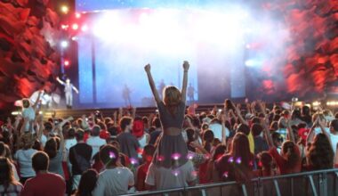 crowds in front of a large concert stage with red and white decorations