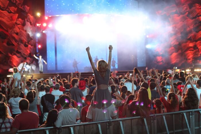 crowds in front of a large concert stage with red and white decorations