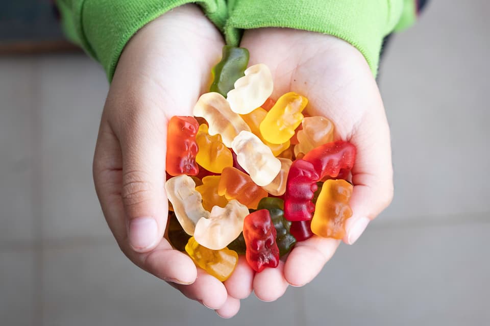 Childs hand holding multi-coloured gummy bears