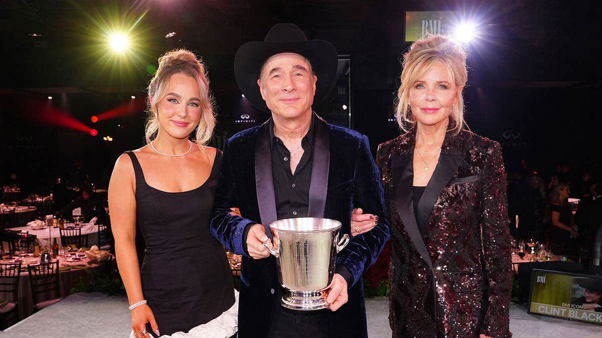 Lily Black, Clint Black and Lisa Hartman Black standing together and holding an award in Nashville.