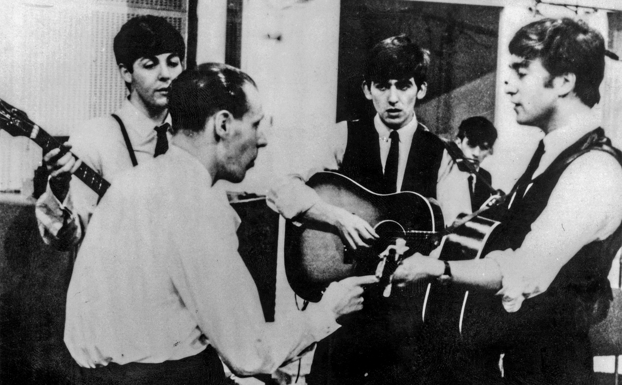 The Beatles at a recording session for the Parlophone label with their producer George Martin, circa 1963
