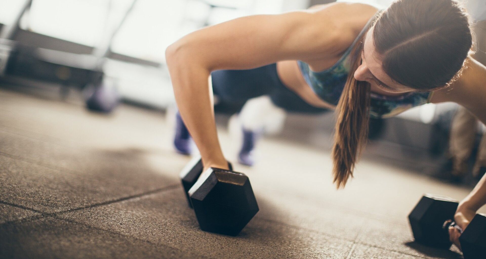 Woman performing a dumbbell push-up during CrossFit style workout