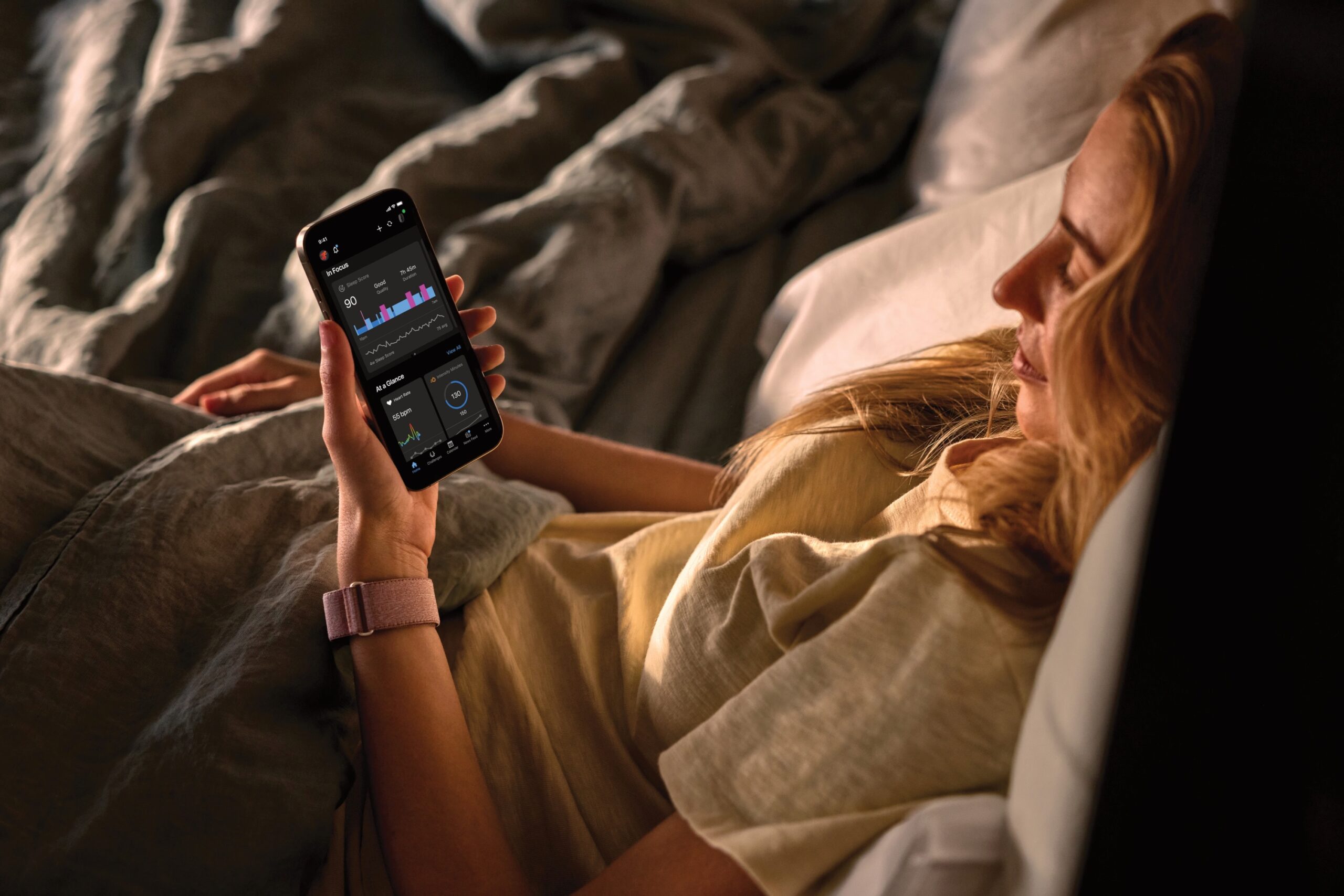 a person lying in bed looking at the Garmin App to check their sleep score.