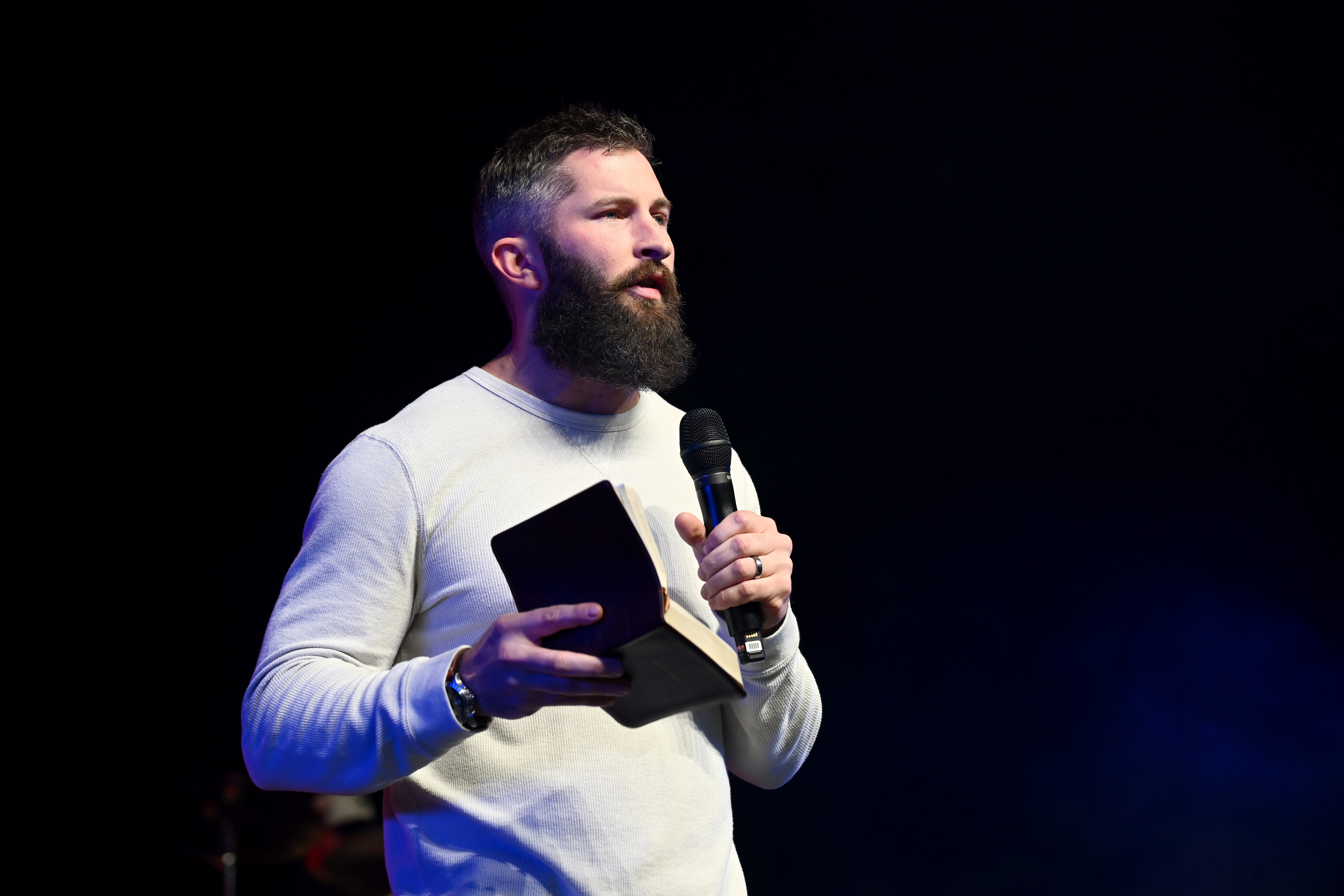 Man speaking, holding a bible.