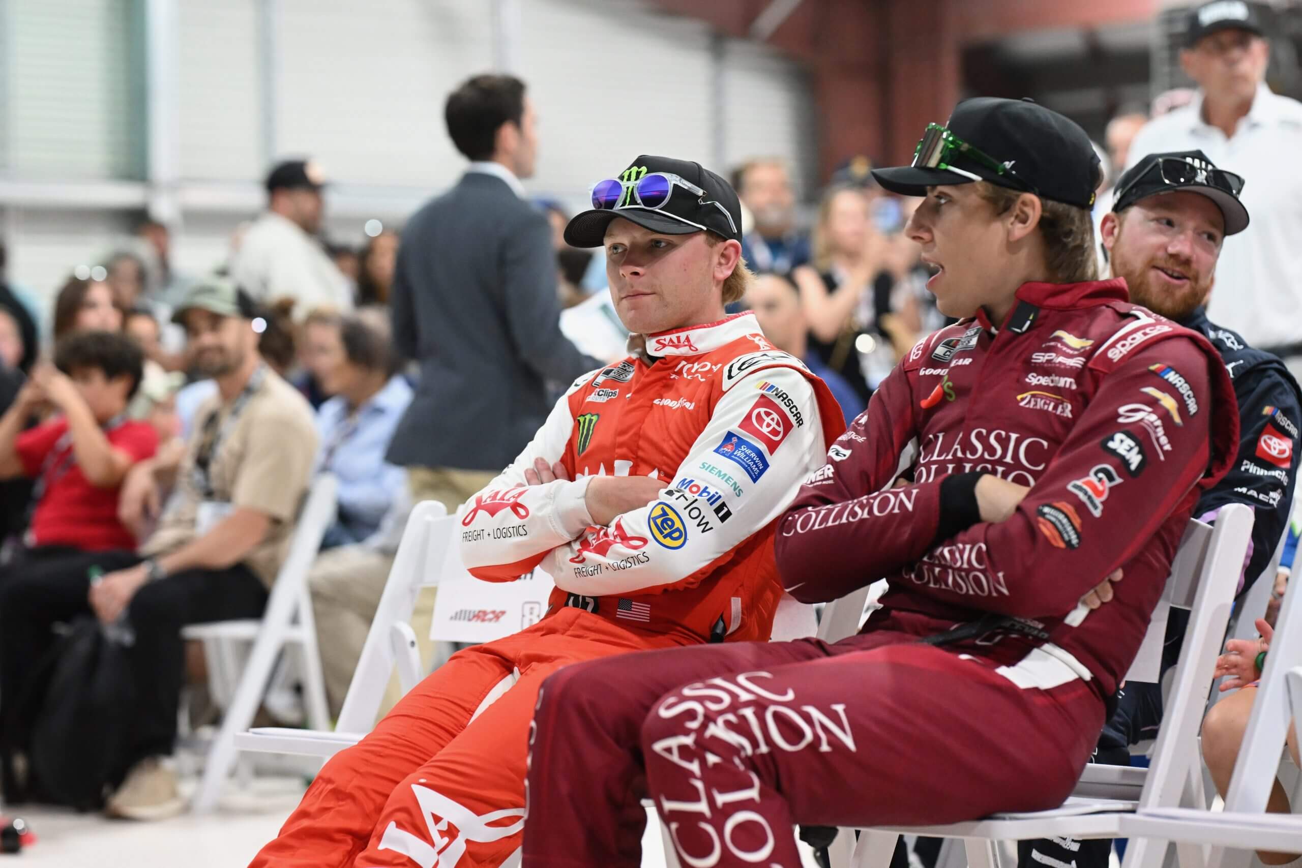 Ty Gibbs and Carson Hocevar sit in chairs with arms crossed.