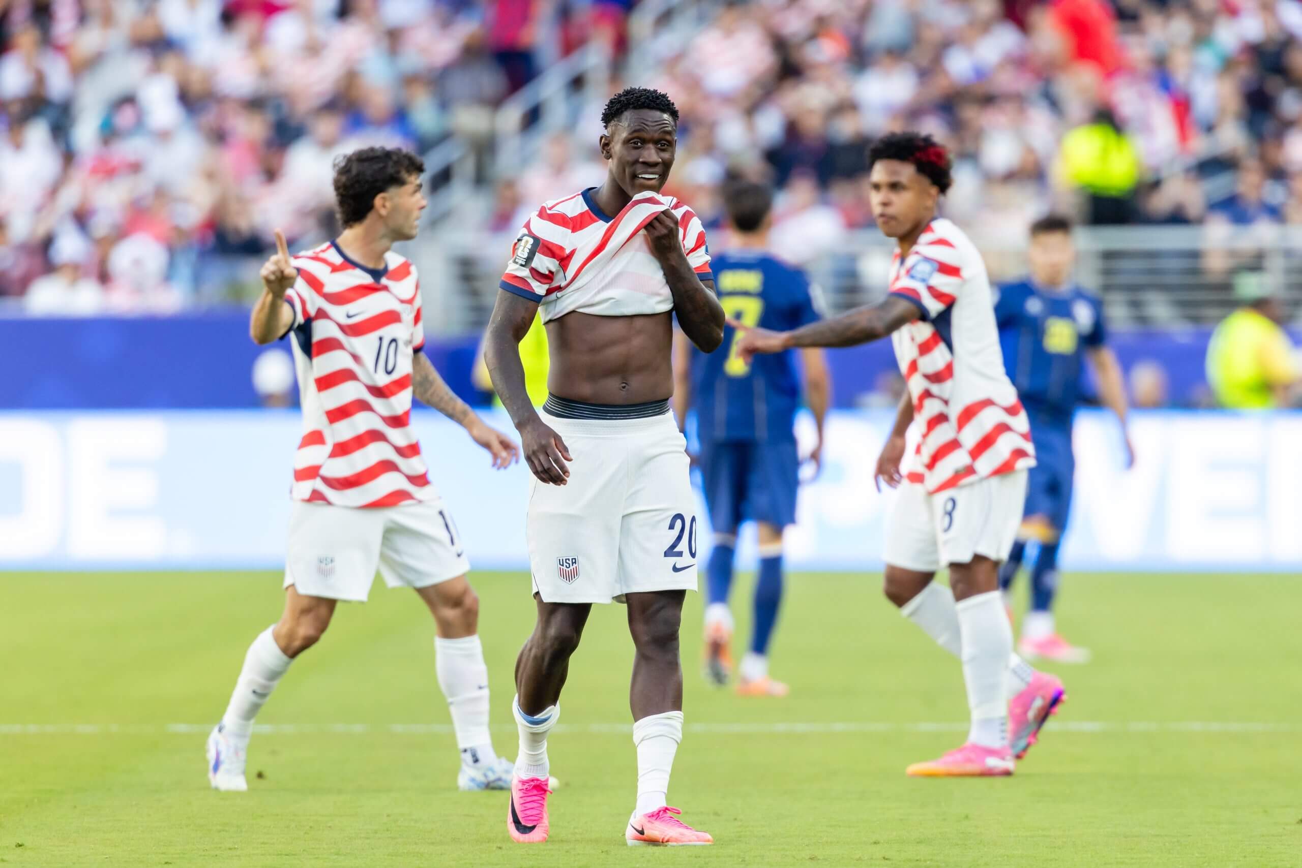 Folarin Balogun looks dumbfounded and pulls up his shirt while team-mates Christian Pulisic and Weston McKennie converse in the background following the USMNT striker's red card against Bosnia and Herzegovina