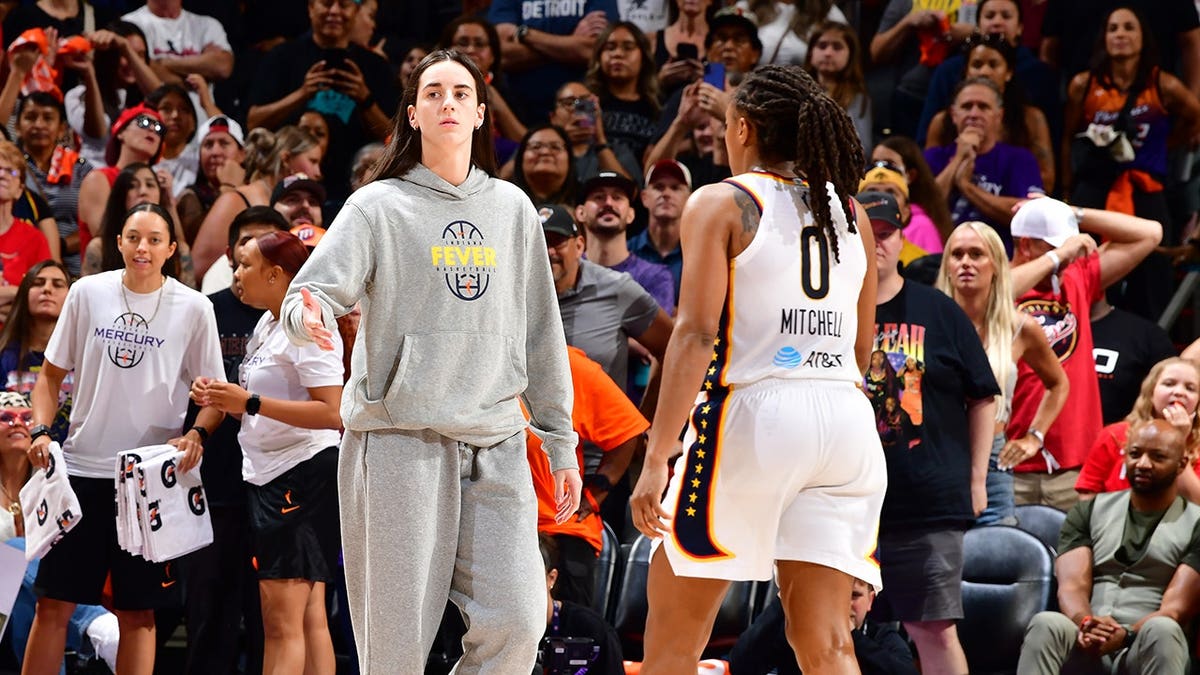 Caitlin Clark, who missed Thursday's game with injury, high fives Indiana Fever teammate Kelsey Mitchell during the game against the Phoenix Mercury.