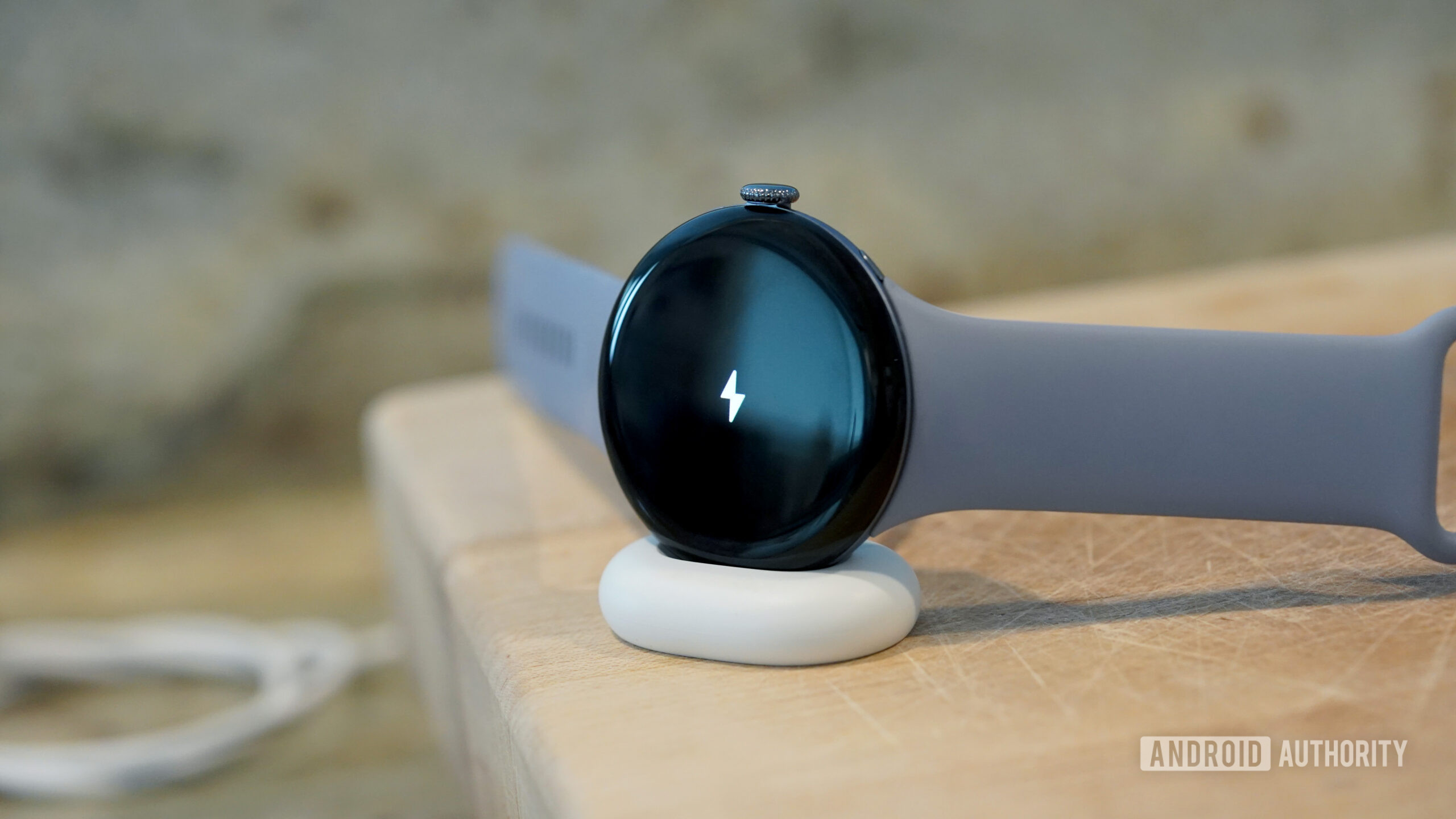 A Google Pixel Watch 4 rests on its charger.